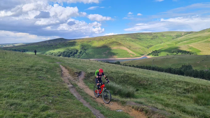 Mountain biker climbing green hill