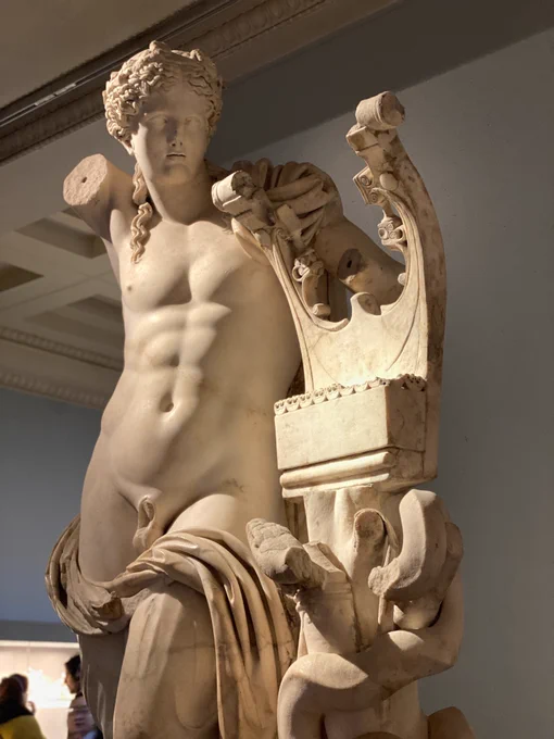 Photo of the original 2nd c. CE Apollo Kithara from Cyrene, on display in the British Museum. The torso and kithara (a type of stringed instrument) are in amazing shape, although Apollo’s right arm is missing (it would have draped on top of his head, as seen in the Koons reconstruction). Photo credit: Chapps