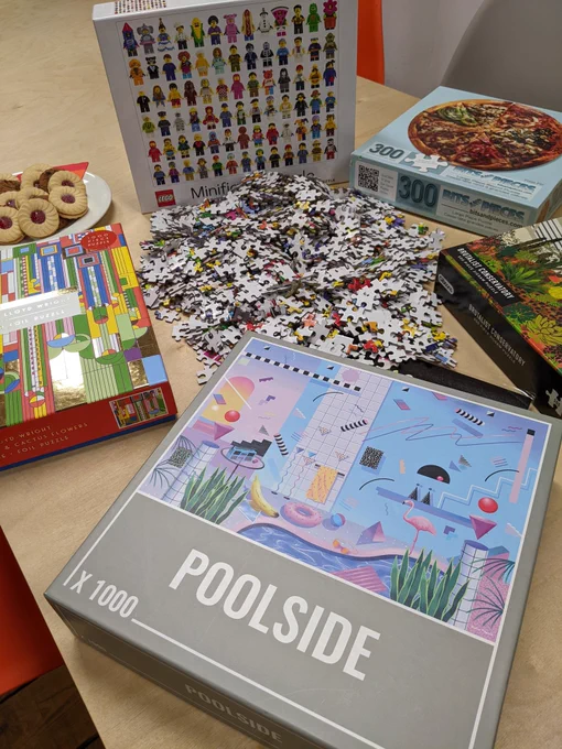 5 jigsaw boxes with loose jigsaw pieces scattered around 