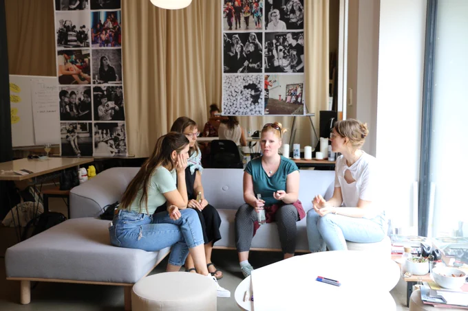 Vier Frauen sitzen auf einem Sofa und unterhalten sich.