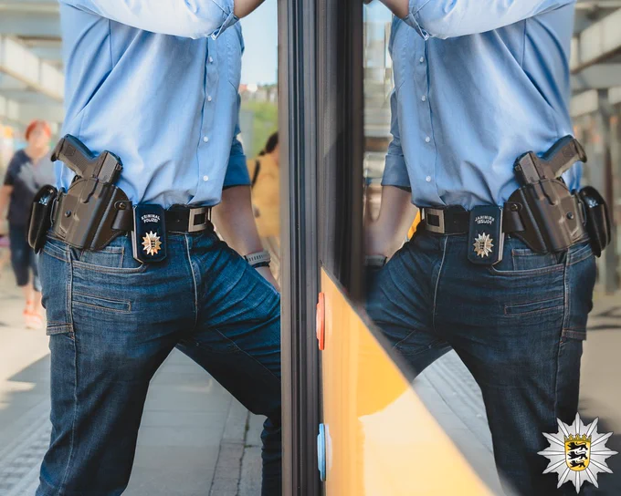 Ein Beamter der Kriminalpolizei mit K-Etui, Dienstwaffe und Handschließen steigt in einen Bus ein.