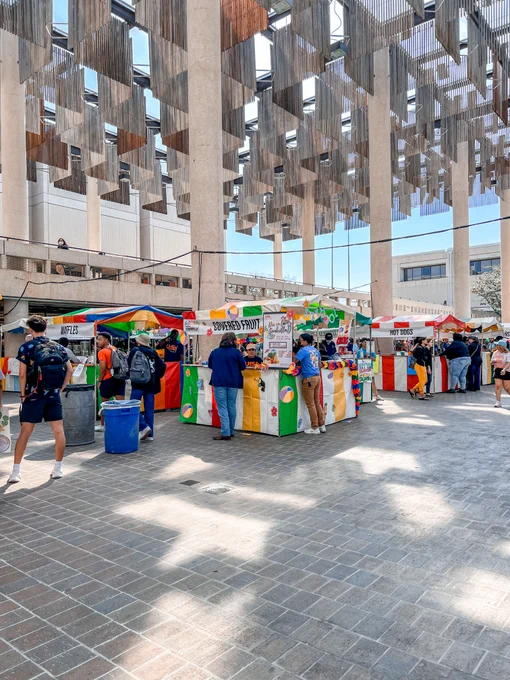 A photo of Dia en la Sombrilla from 2022. The photo shows an early shot of the day, with a few people visiting booths.