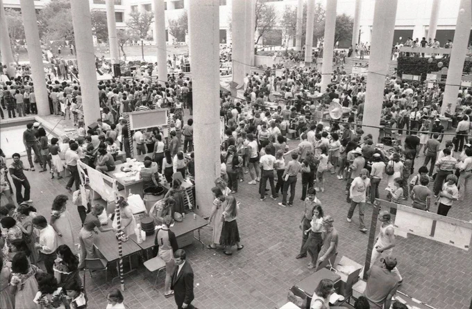 A photo of Dia en la Sombrilla (formerly Fiesta UTSA) from 1982. It is in black and white and shows a lot of people mingling in the sombrilla. 