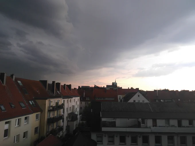 Dunkle Gewitterwolken auf der einen Himmelhälfte. Blauer Himmel auf der anderen Hälfte.