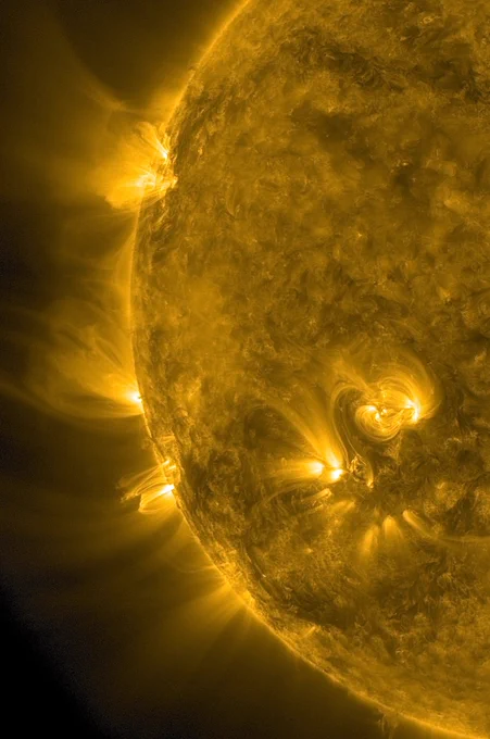 Derselbe Bildausschnitt wie gestern mit Zoom auf die linke Seite der Sonne in gelber Darstellung. Oben auf der Zeigerposition zehn Uhr und auch darunter an mehreren Stellen am Rand weit ins All reichende Strahlen. Sie gehen von gleißend hell erscheinenden Gebieten aus, beschreiben große Kurven und teils auch Bögen und verlieren sich mit zunehmender Entfernung im Schwarz des Alls. Insgesamt zeigt der Bildausschnitt sechs bis sieben solcher Aktiven Regionen, vier davon am Rand, die anderen weiter rechts auf der Oberfläche - immer aus dem Blickwinkel des Satelliten gesehen, der sich rund sechsunddreißig tausend Kilometer über der Erde befindet, also die hundertfünfzig Millionen Kilometer entfernte Sonne aus unserer irdischen Perspektive beobachtet.