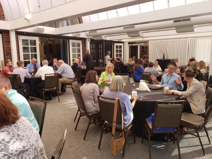 Several tables of Oklahoma School Innovation Summit attendees eating breakfast and talking with each other.
