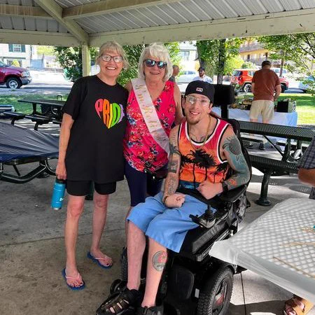 Mary outside wearing a retirement sash and standing next to two people.