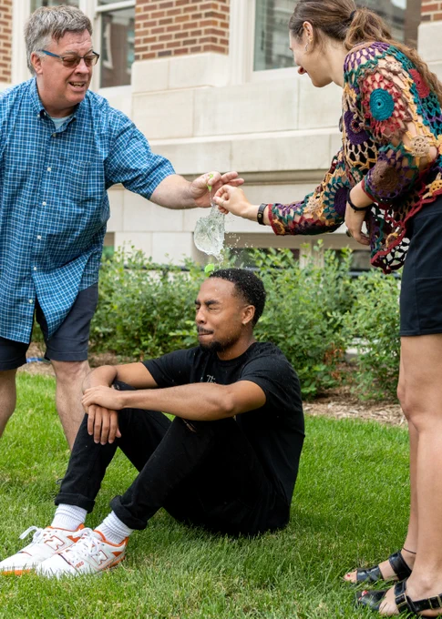 Instructor Bradley WIlson and Western Kentucky University student Rhiannon Johnston pop a balloon over the head of Morehouse College student Chris Doomes at the Associated Collegiate Press Mega Workshop in Minneapolis July 16, 2022.