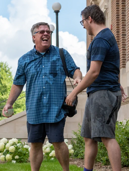 Instructor Bradley Wilson laughs with Eastern Illinois University student Rob Le Cates after both had been splashed by water balloons during a photo activity at the Associated Collegiate Press Mega Workshop in Minneapolis July 16, 2022. 