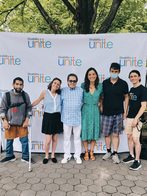 Photo of Carlina Rivera with disability rights advocates in front of the disability unite backdrop for a photo.