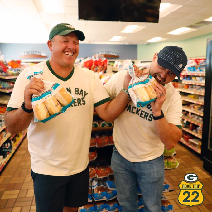 Tony Moll laughs at Jason Spitz jokingly acting like he's taking a bite out of a bag of bread at Kwik Trip.