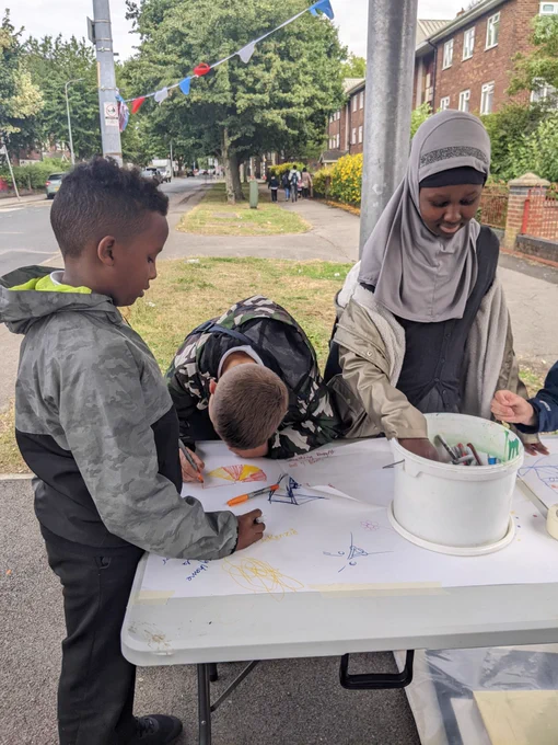 A group of children drawing on a large piece of white paper. 