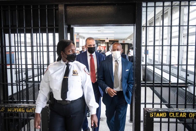 Mayor Adams and a guard walk through a gate on Rikers Island