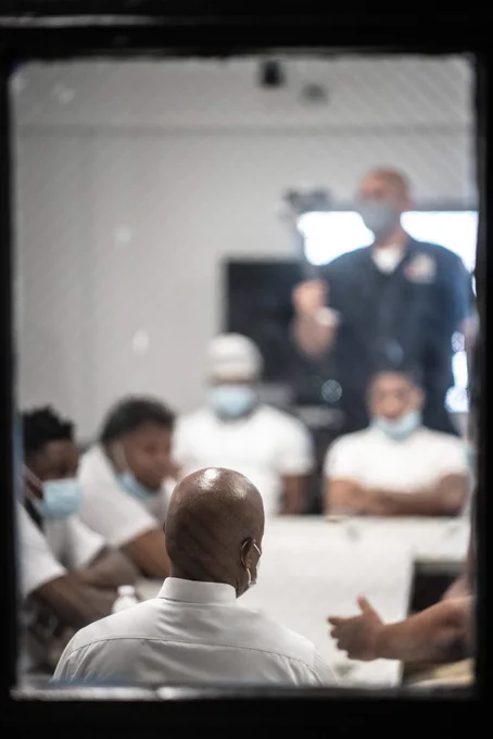 A shot over Mayor Adams’ shoulder of the room. People in custody and corrections officers speak to him.