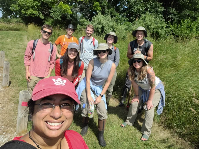 Nine people standing in a natural area.