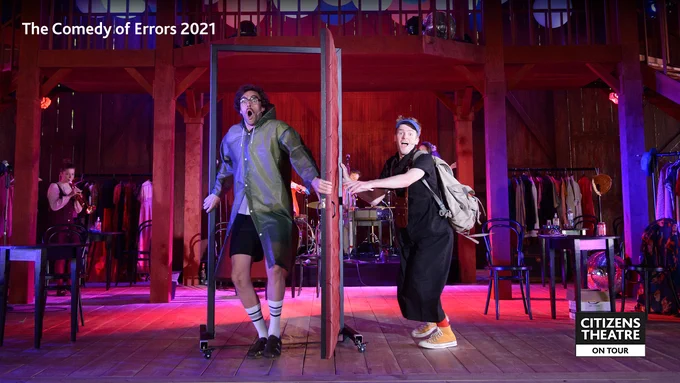 A stage production, two young men standing either side of a door. Text that reads The Comedy of Errors 2021.