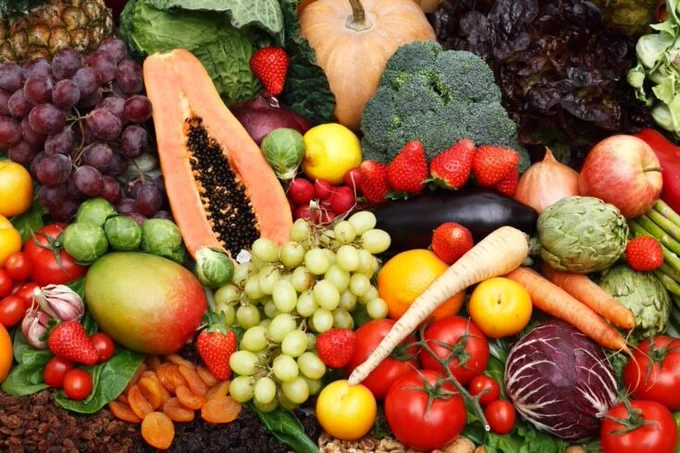 A spread of fruit and vegetables, including grapes, papaya, strawberries, apples, dried apricots, tomatoes, carrots, brussel sprouts and artichokes. 