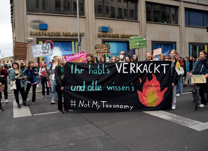 Fridays for Future Denonstrat*innen stehen vor dem EU Kommissionsgebäude in Berlin hinter einem Transpi auf dem steht "ihr habt's verkackt und alle Wissen's - #NotMyTaxonomy"