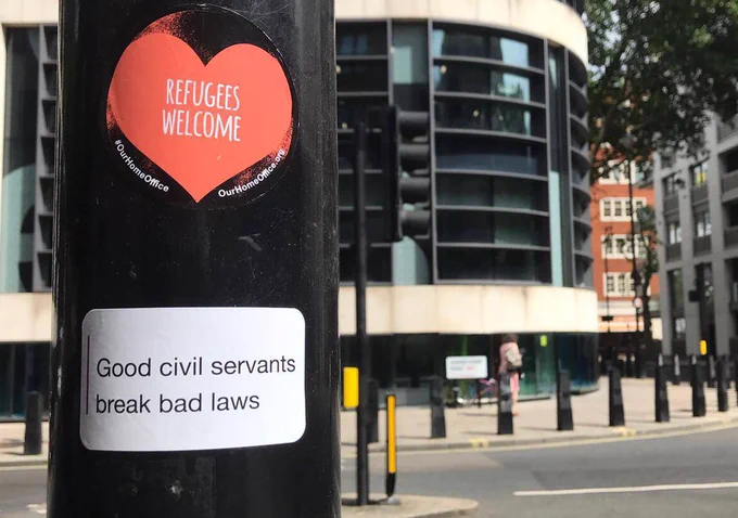 Stickers on Westminster lamppost: refugees welcome and good civil servants break bad laws