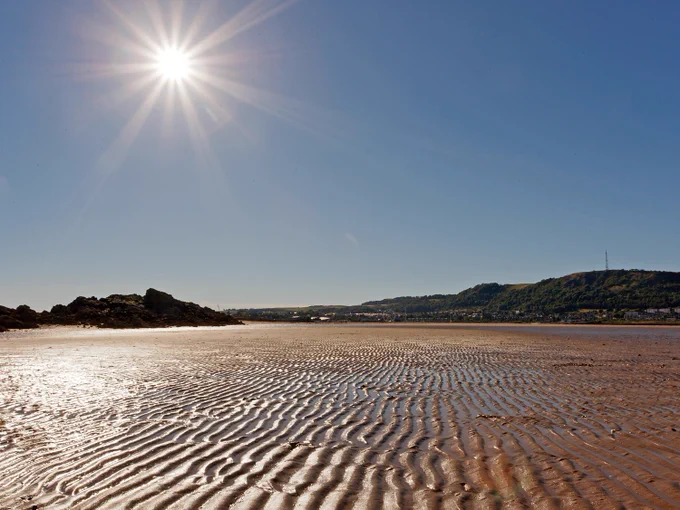 Blazing sun high in the sky, ripples in the sands at low tide