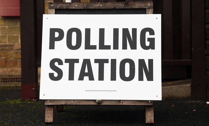 A polling station sign displayed outside a building