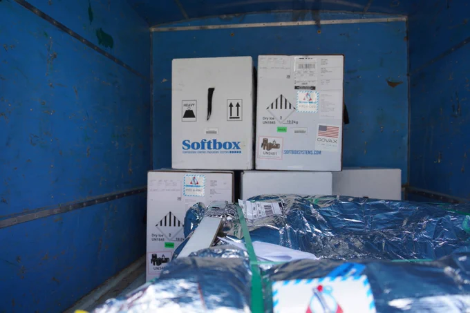 Boxes of COVID-19 vaccines await transport in the cargo bay of a delivery truck.