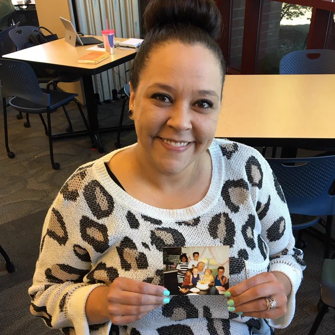 Woman smiling, holding childhood photo