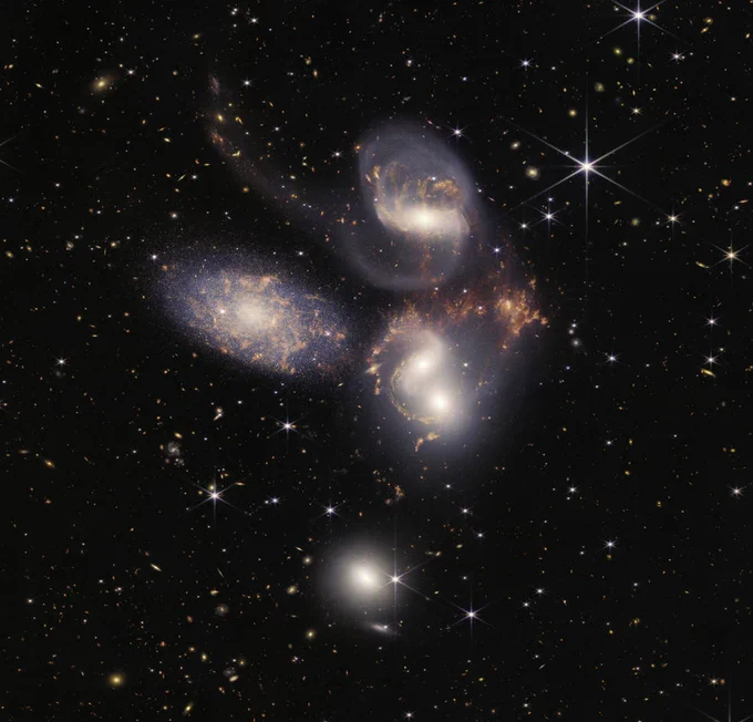 This image of Stephan’s Quintet, a visual grouping of five galaxies, is contains over 150 million pixels and is constructed from almost 1,000 separate image files. Sparkling clusters of millions of young stars and starburst regions of fresh star birth grace the image. Sweeping tails of gas, dust and stars are being pulled from several of the galaxies due to gravitational interactions. Most dramatically, Webb captures huge shock waves as one of the galaxies, NGC 7318B, smashes through the cluster. Credits: NASA, ESA, CSA, and STScI