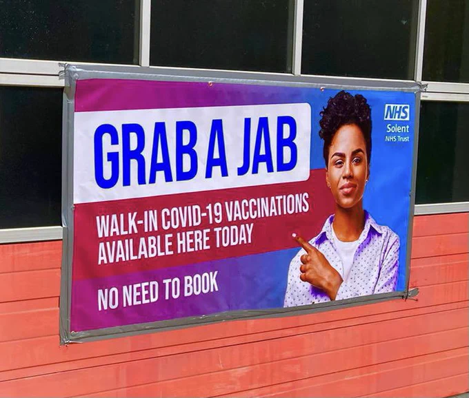 Solent NHS Trust banner on fire station appliance bay doors. 

‘Grab a jab - walk in Covid-19 vaccinations available here today - no need to book’