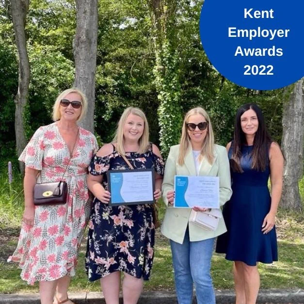 Four people standing under trees. Two of them holding certificates from the Kent Employers Awards 2022