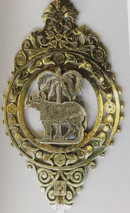 Ornate gold metal badge with rhino & palm tree at centre of circular design. Presidential badge for Faculty of the History & Philosophy of Medicine and Pharmacy at the Worshipful Society of Apothecaries 