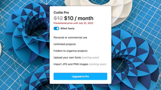 A promo for Cuttle Pro. $12 crossed out, $10 / month. Promotional price until July 22, 2022. Billed Yearly. Personal or commercial use. Unlimited projects. Folders to organize projects. Upload your own fonts (coming soon). Import JPG and PNG images (coming soon). Upgrade to Pro. Cardstock torus sculptures on a cutting mat in the background.