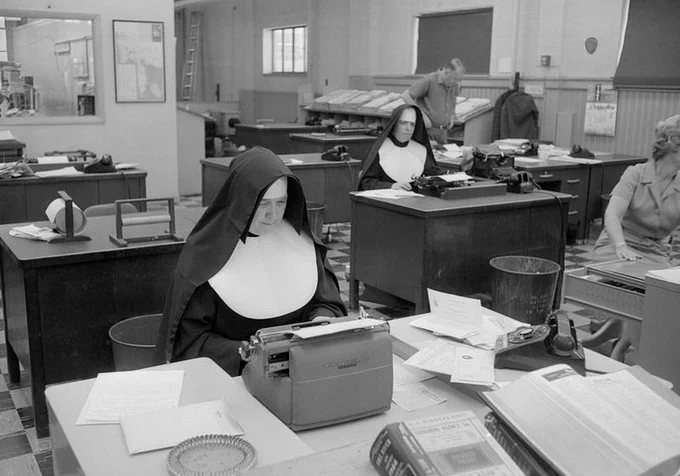 Photograph of two nuns sitting in front of typewriters in a newsroom, 1964. Caption: Nun working in city room, Standard-Times newspaper, Pleasant Street, New Bedford.