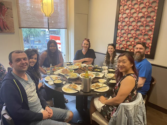 The ServerlessDays Amsterdam organiser team around a table with lots of food on a lazy susan.