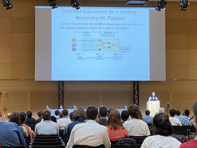 Photo: IJCAI Computers and Thought Award lecture by Bo Li. Slide title reads “Certified Robustness for a Sensing-Reasoning ML Pipeline”