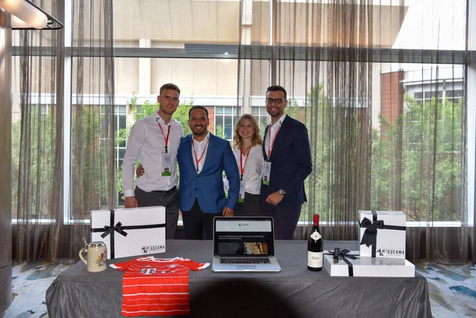 4 students standing side by side behind a table.