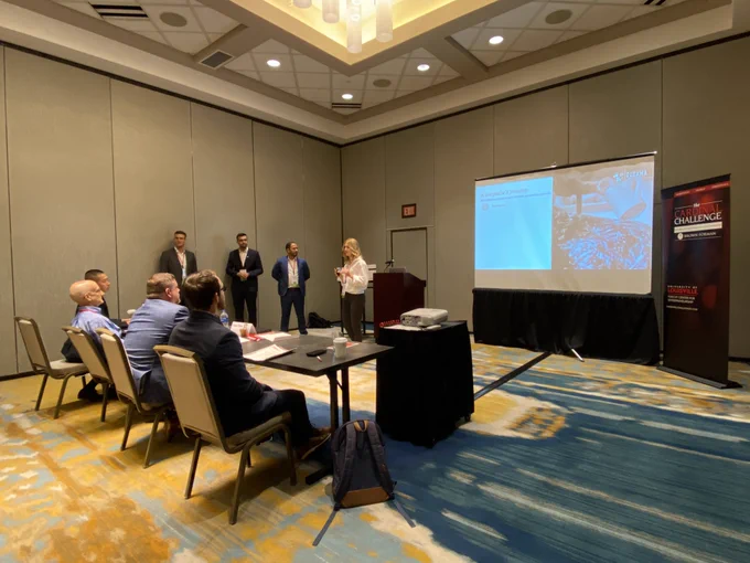Group of students in a conference room giving a presentation.