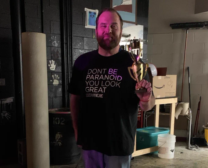 Brad holds his award backstage. He is wearing a t-shirt that reads, “Don’t be paranoid you look great.”