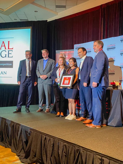 People standing on stage with an award for the Fast Pitch Competition.