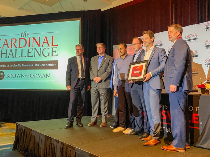 People standing on stage with an award for third place in the Business Plan Presentations. 