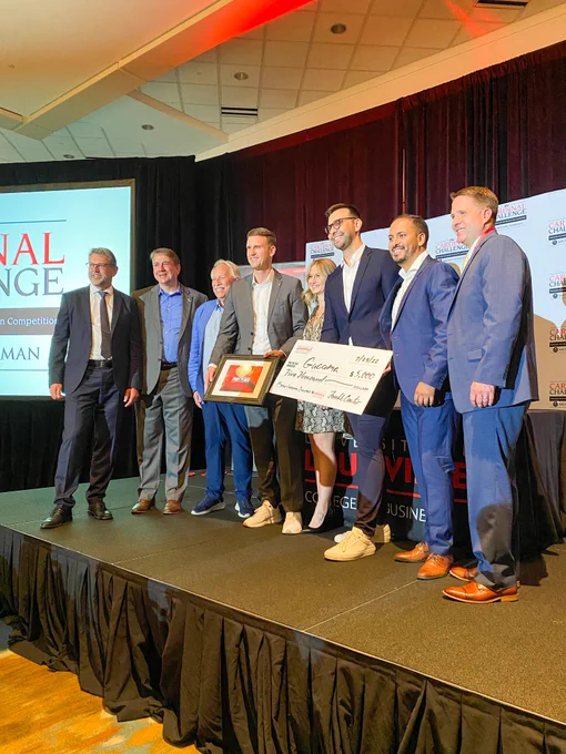 People standing on stage with an award for first place in the Business Plan Presentations. 