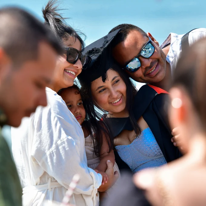 A grad poses with loved ones outside