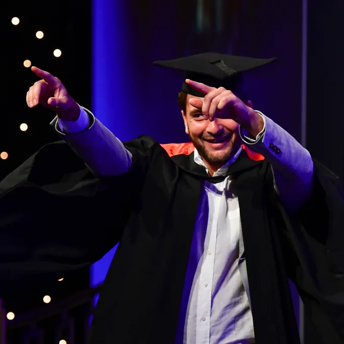 a grad strikes a pose on stage