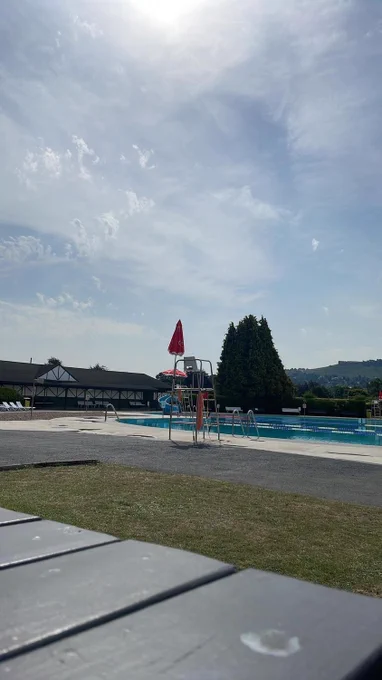 Outdoor swimming pool at Ilkley on a sunny day with a lifeguard's chair in the middle of the image