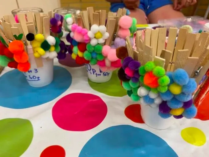 Wooden pegs with flowers made of pom poms stuck on.