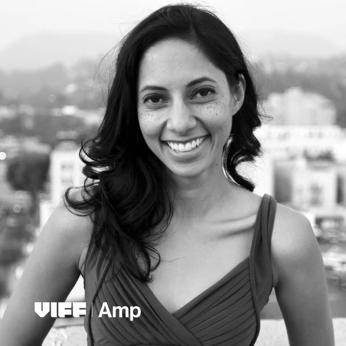 Black and white photo of Amritha Vaz with a blurred background of a city view.