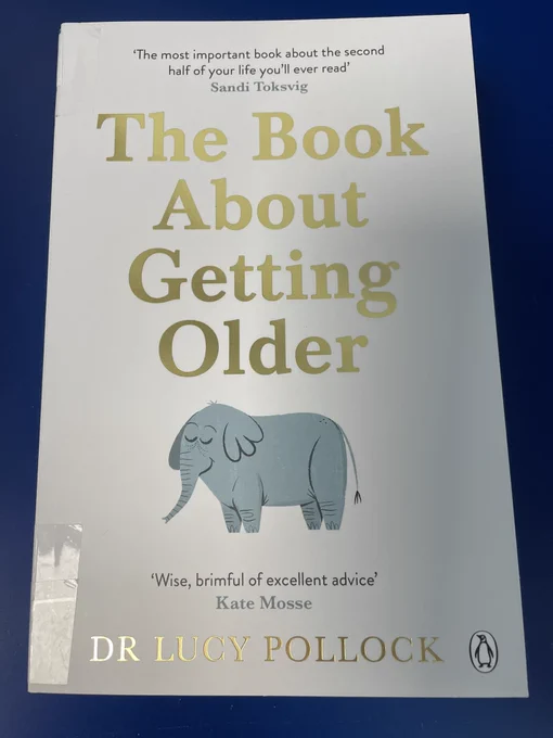 The front cover of paperback edition of The Book About Getting Older by Dr Lucy Pollock placed on a blue library trolley. Photo by tweet author.