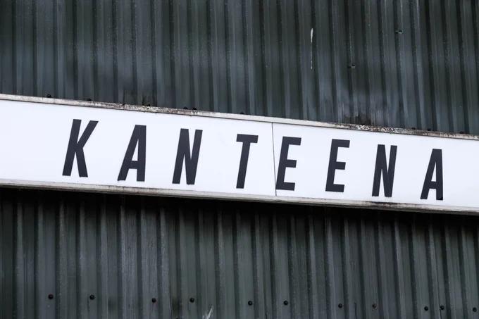 Picture of the Kanteena venue sign on the outside of the building, white background with Kanteena in black italic text. 