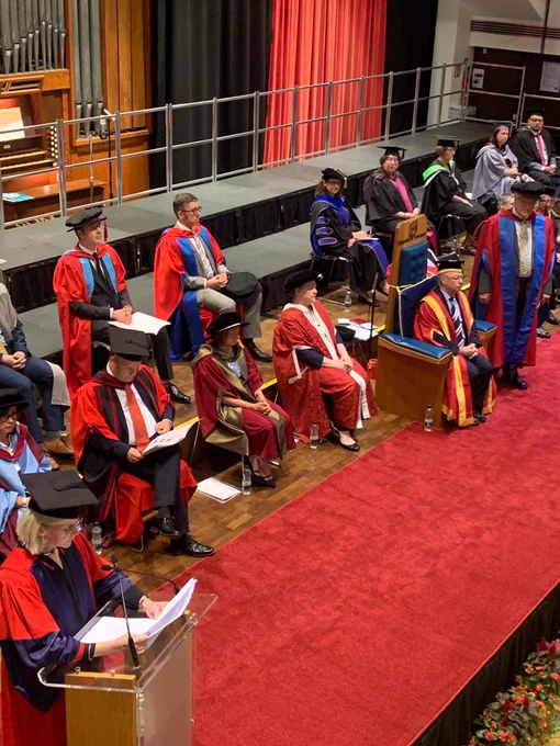 A raised view of the graduation stage within the Great Hall, as Professor Sandra Kemp speaks from the lectern
