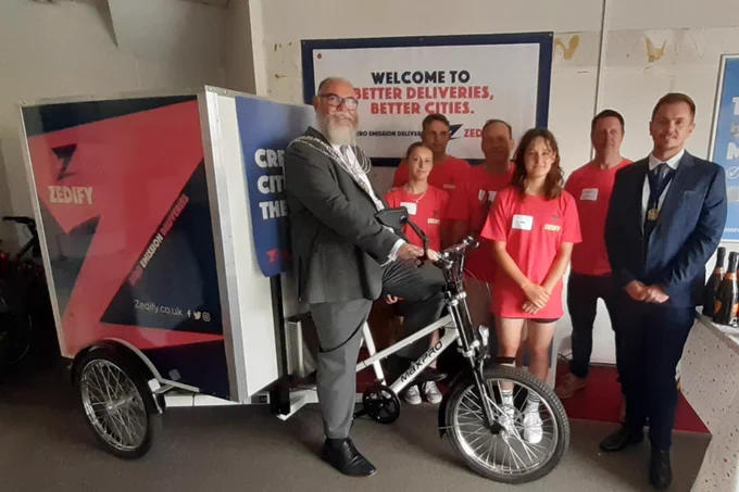 The Deputy Lord Mayor sitting on a Zedify courier bike - also in the picture are members of the Zedify team in red t-shirts and the Deputy Lord Mayor’s Consort